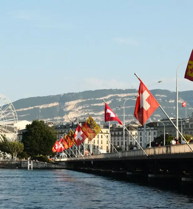 the Pont des Bergues bridge in Geneva, Switzerland, adorned with Swiss flags and flags of the Canton of Geneva.